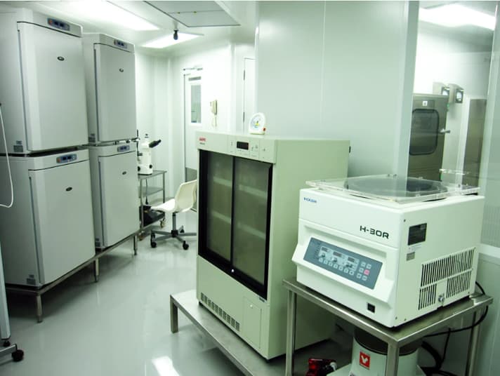 A wide view of NiSCELL cleanroom equipment: upright freezers, an incubator and a centrifuge along the wall of a suite.